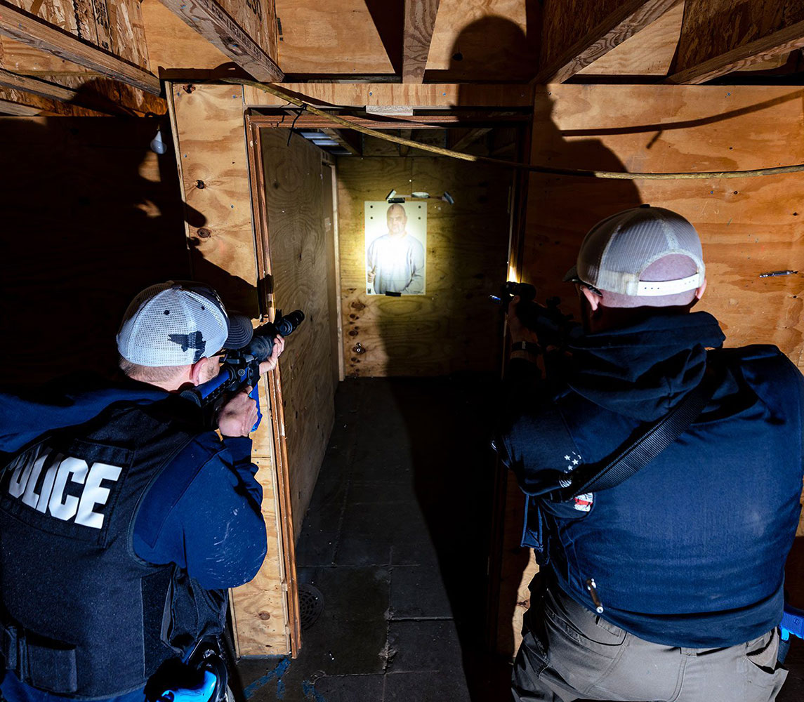two males outside of small room in advanced high threat training course